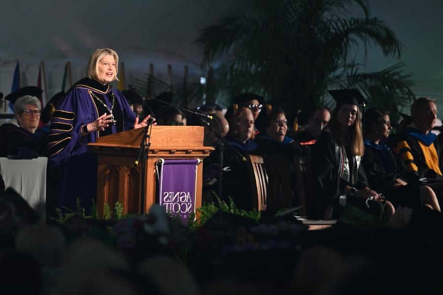 聚光灯聚焦在一位身穿紫黑长袍的大学校长身上. 